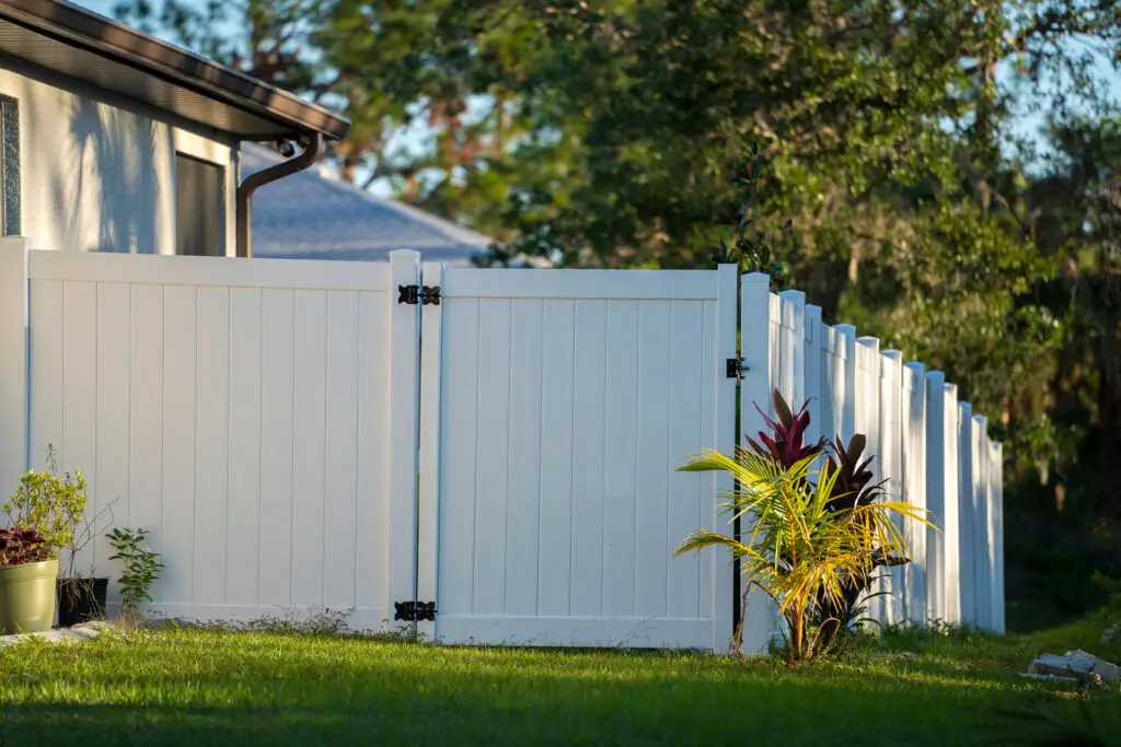 White vinyl privacy fence on green lawn surrounding property