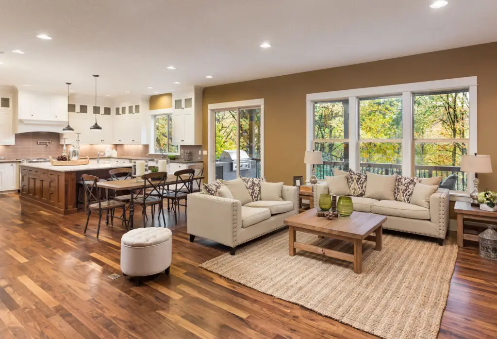 Living room with dark hardwood flooring connected to an open kitchen and dining area