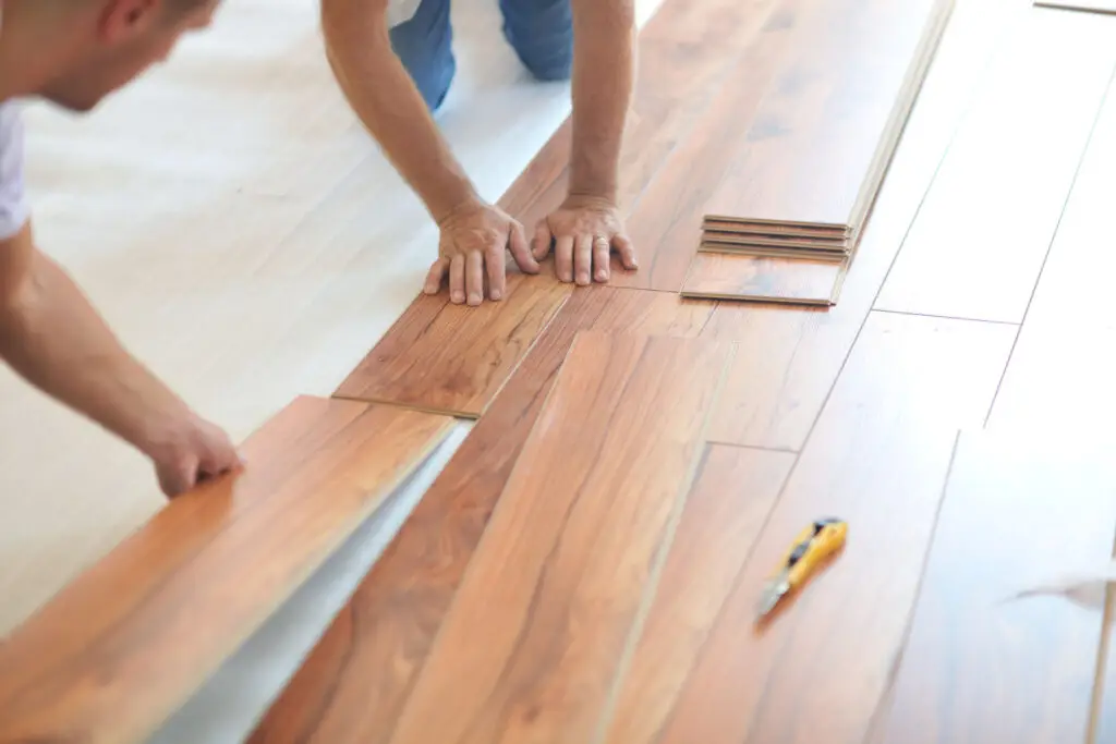 Workers installing luxury vinyl plank flooring in a home