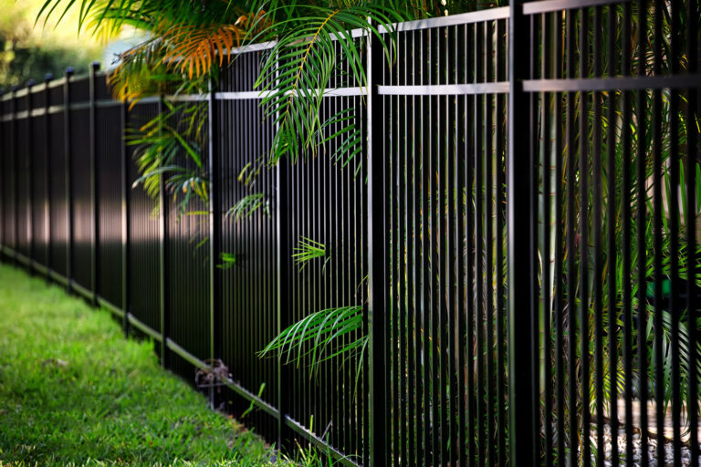 Black aluminum fence with foliage poking through